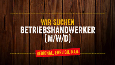 Stellenausschreibung für Betriebshandwerker (m/w/d) auf Holz-Hintergrund mit der Aufschrift „Wir suchen Betriebshandwerker (m/w/d) – Regional, ehrlich, nah.“
