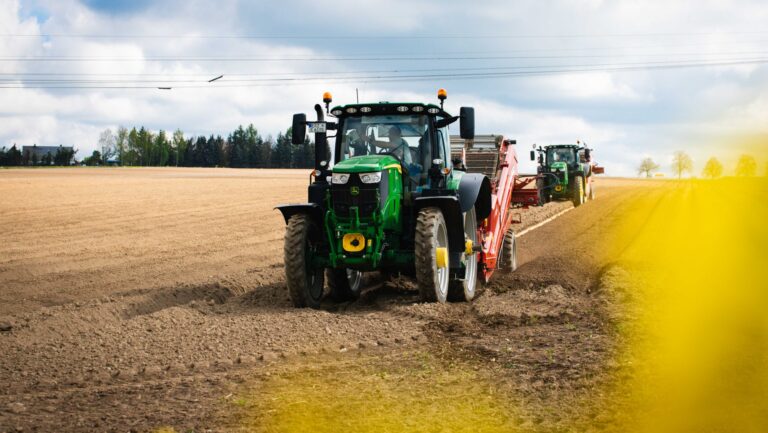 Moderne Traktoren bei der Feldbestellung auf einem Acker unter bewölktem Himmel – landwirtschaftliche Maschinen im Einsatz bei der Frühjahrsaussaat