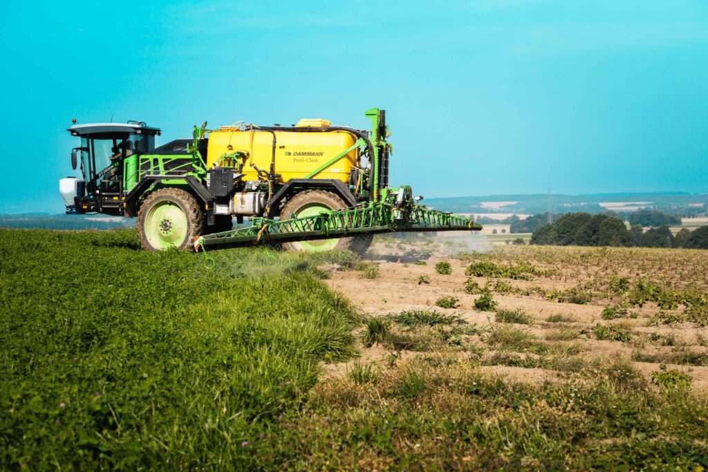 2. Ein Traktor mit Sprühgerät behandelt ein Feld mit Pflanzenschutzmitteln