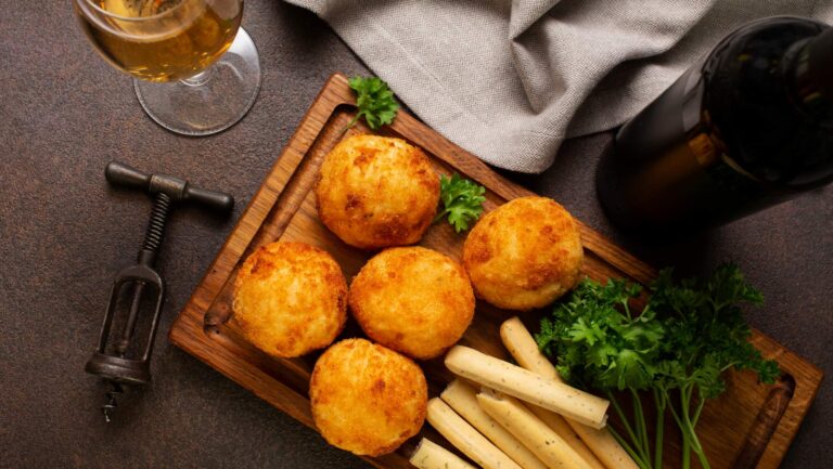 Leckere frittierte, goldbraune und knusprige Kartoffelbällchen mit Kräutern auf einem Tablet