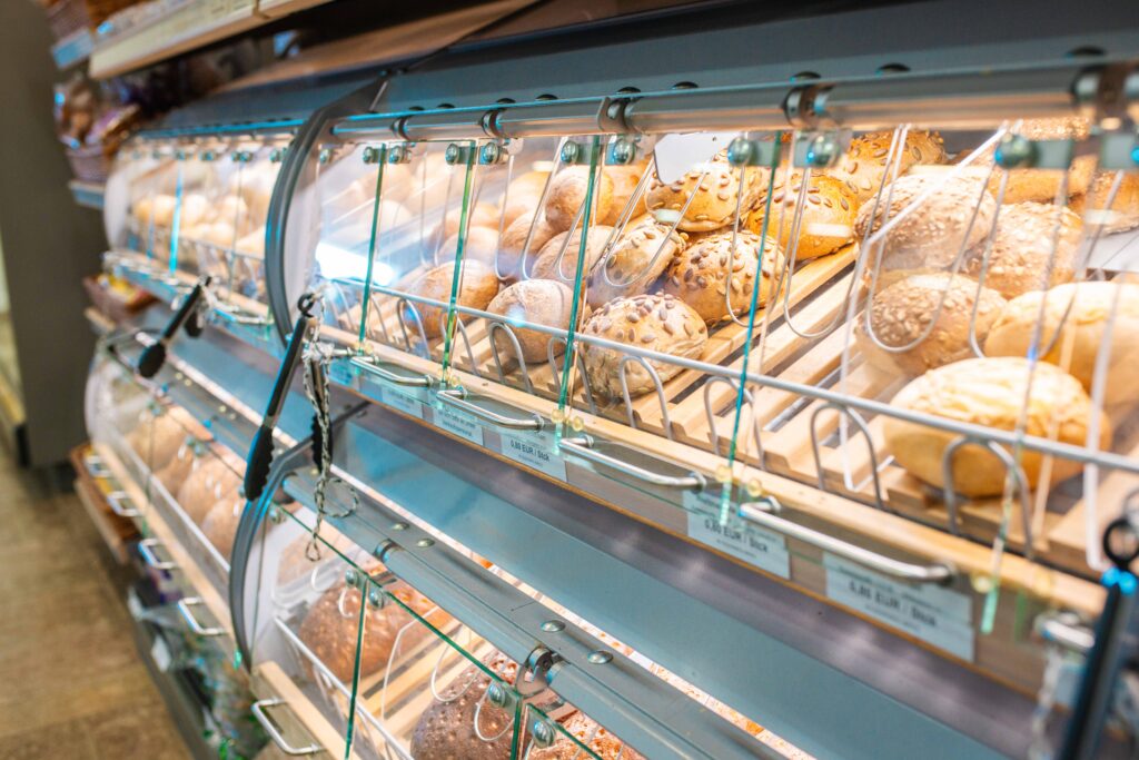 Frische Brötchen und Backwaren hinter Glas in der SB-Bäckertheke eines Supermarktes.