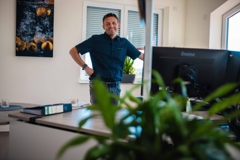 Ein lächelnder Mitarbeiter von Friweika an seinem modernen Büro-Arbeitsplatz.