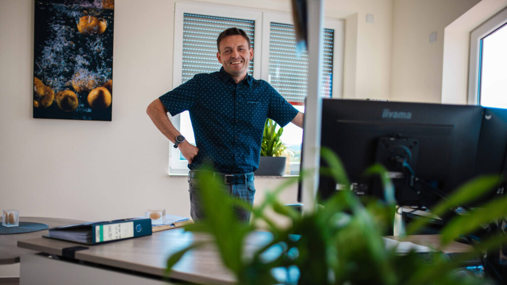 Ein lächelnder Mitarbeiter von Friweika an seinem modernen Büro-Arbeitsplatz.