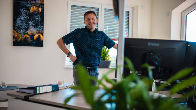 Ein lächelnder Mitarbeiter von Friweika an seinem modernen Büro-Arbeitsplatz.