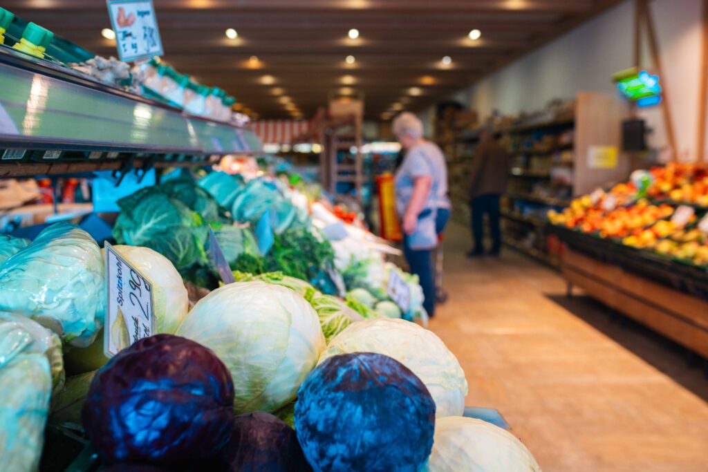 Frisches Obst und Gemüse im Friweika Werksverkauf: Vielfältiges Angebot an Kohlköpfen im Vordergrund und einladende Gänge mit regionalen Produkten.