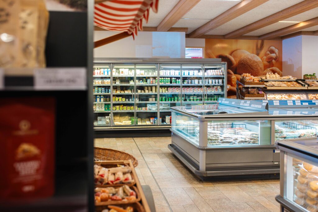 Gekühlte Frischeprodukte im Friweika Werksverkauf: Blick auf Molkereiprodukte im Wandkühlregal und Tiefkühlkost in modernen Verkaufstruhen.