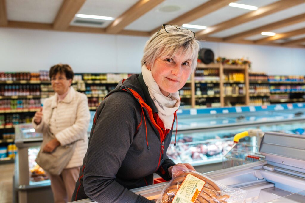 Einkaufserlebnis bei Friweika: Eine Mitarbeiterin wählt frische Fleischwaren aus der Tiefkühltruhe im gut sortierten Werksverkauf mit regionalen Spezialitäten.