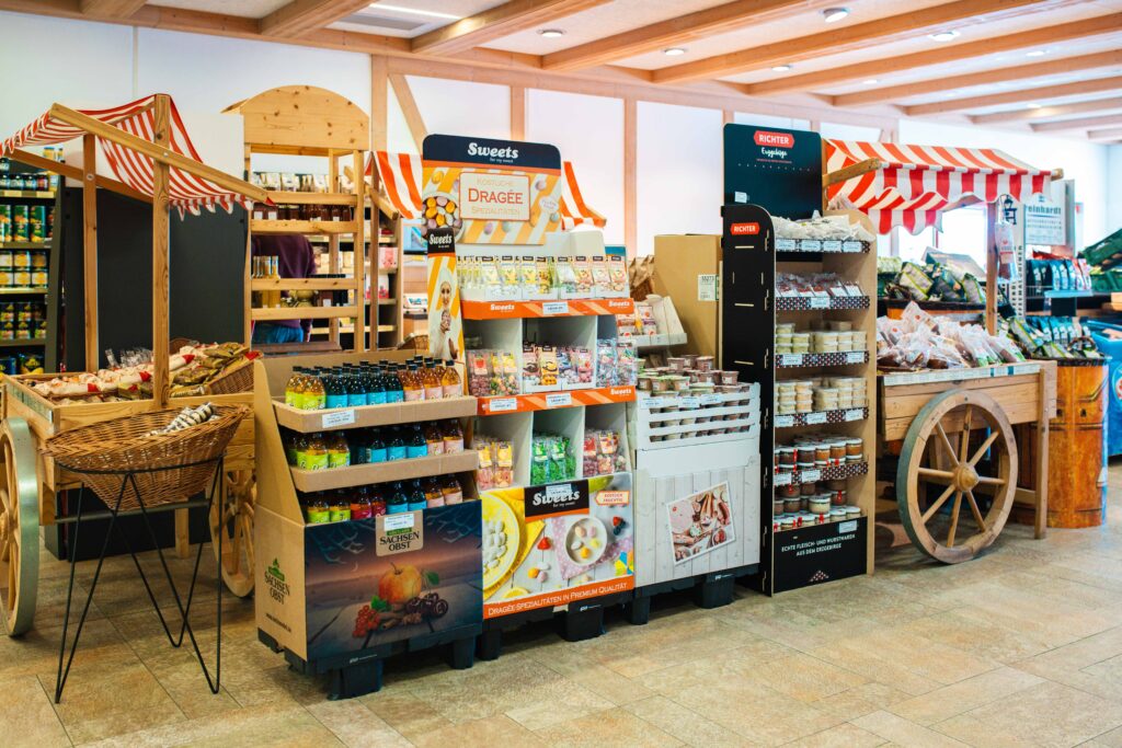 Regionale Präsente und Süßwaren im Friweika Werksverkauf: Dekorative Marktkarren mit Säften von Sachsenobst, Dragée-Spezialitäten und regionalen Feinkost-Artikeln.