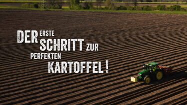 Ein grüner Traktor bei der Feldarbeit zieht präzise Furchen in einen weitläufigen Acker zur Kartoffel-Aussaat unter dem Slogan „Der erste Schritt zur perfekten Kartoffel!“.
