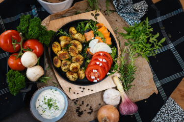Gebratene Rosmarinkartoffeln mit buntem Salat, Tomatenscheiben und Quark-Dip, angerichtet mit frischen Zutaten