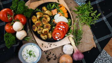 Gebratene Rosmarinkartoffeln mit buntem Salat, Tomatenscheiben und Quark-Dip, angerichtet mit frischen Zutaten