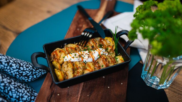 Überbackene Kartoffelscheiben mit Crème fraîche und Schnittlauch in schwarzer Auflaufform
