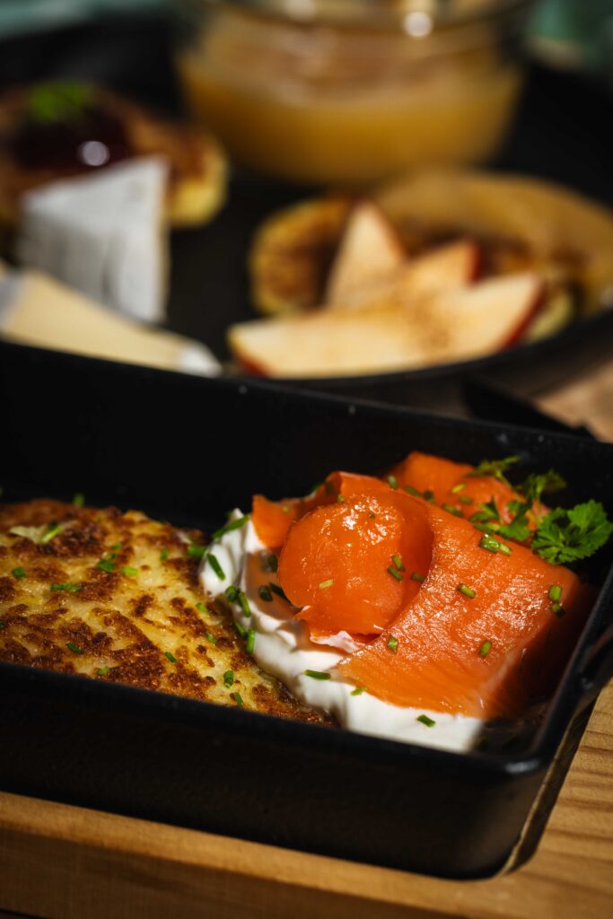 Nahaufnahme von Kartoffelpuffer mit Schmand, Räucherlachs und Schnittlauch
