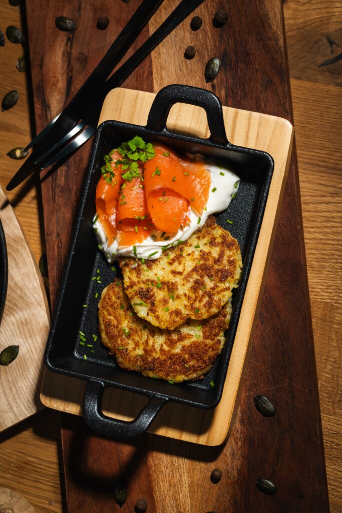 Kartoffelpuffer mit Räucherlachs und Schmand im Gusseisenpfännchen von oben