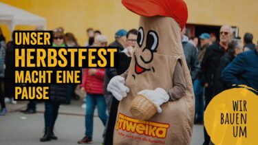 Das Maskottchen, eine als Kartoffel gekleidete Figur mit dem Logo der Kartoffelspezialitätenmarke Friweika, ist vor dem Hintergrund eines Marktplatzes zu sehen. Auf der linken Seite befindet sich ein gelbes Schild mit der Aufschrift „UNSER HERBSTFEST MACHT EINE PAUSE“. Auf der rechten Seite befindet sich ein gelbes Schild mit der Aufschrift „WIR BAUEN UM“. Das Maskottchen trägt eine rote Baseballkappe, weiße Handschuhe und hält einen Korb in der Hand.