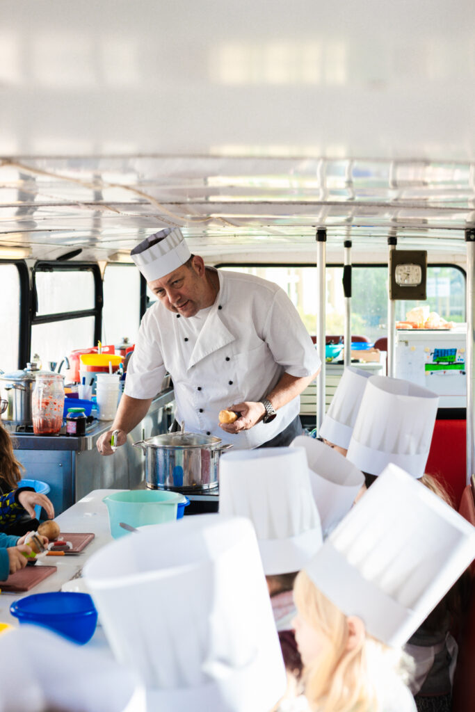 Koch erklärt Kindern das Kochen im Kochbus