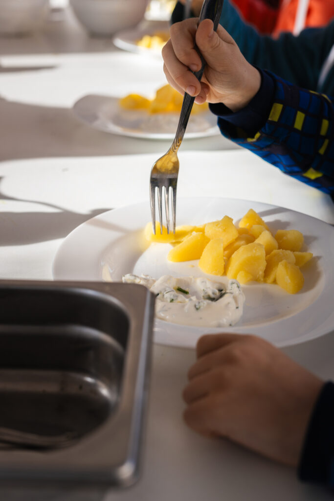 Kind isst gekochte Kartoffeln mit Kräuterquark mit einer Gabel